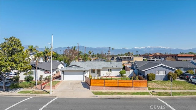 ranch-style house with a garage, a residential view, a mountain view, and a fenced front yard