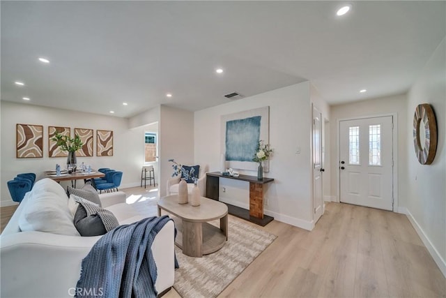 living area featuring light wood-type flooring, baseboards, and plenty of natural light