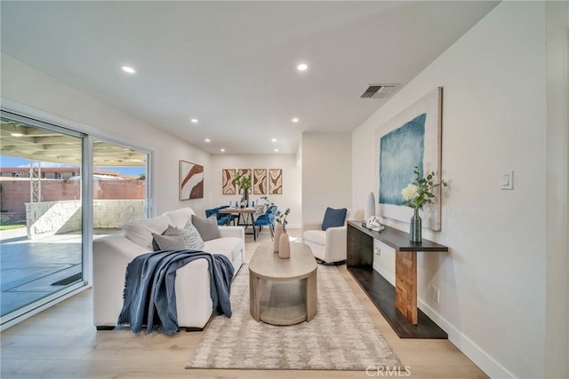living area featuring visible vents, light wood-type flooring, recessed lighting, and baseboards