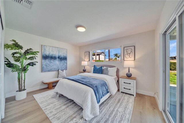 bedroom with visible vents, light wood-style flooring, and baseboards