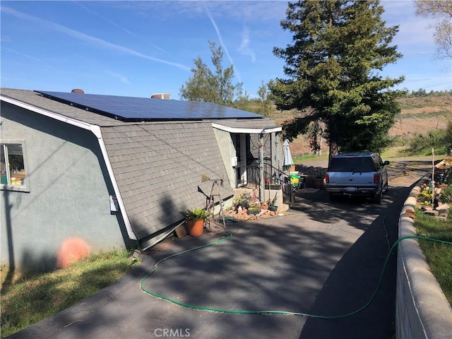 view of home's exterior with roof mounted solar panels and stucco siding