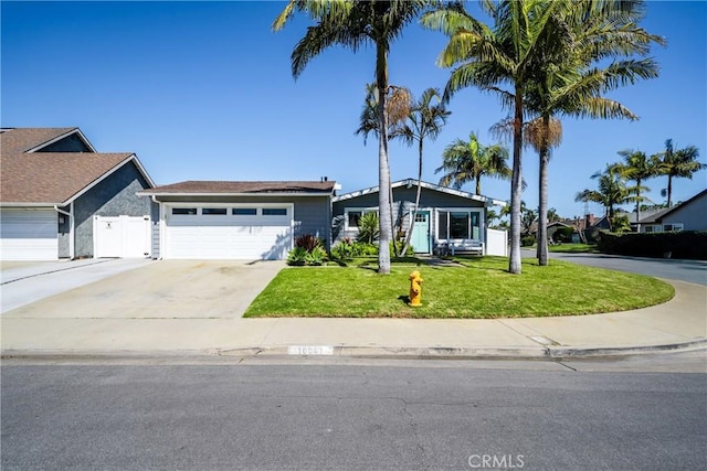 view of front facade with a front yard, fence, a garage, and driveway