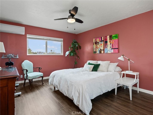 bedroom with wood finished floors, baseboards, a wall mounted air conditioner, and ceiling fan