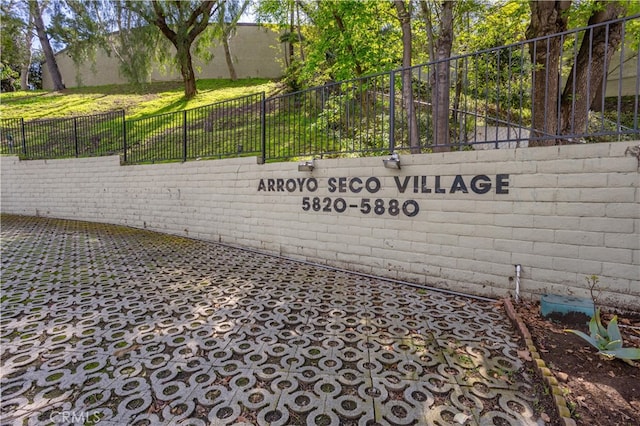 community / neighborhood sign with fence and a lawn