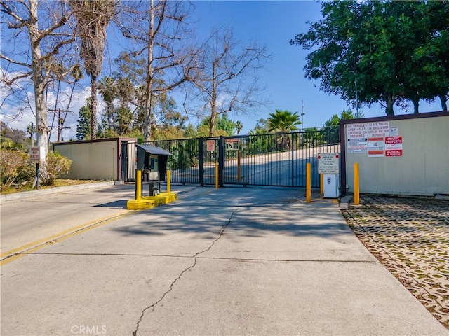 view of road featuring a gated entry, curbs, and a gate