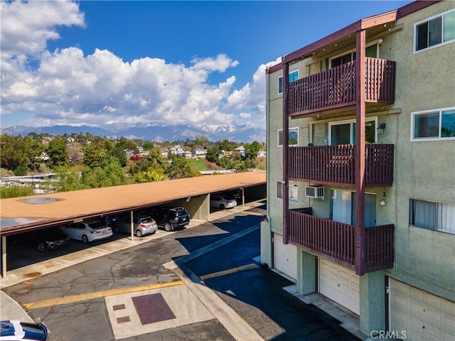 view of building exterior featuring a mountain view and covered and uncovered parking