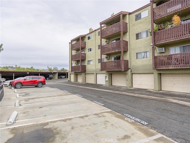 view of property featuring uncovered parking and a wall mounted AC