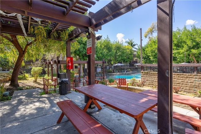 view of patio with a community pool, outdoor dining space, and fence