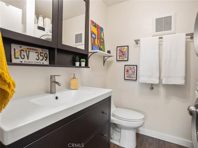 bathroom with vanity, toilet, baseboards, and visible vents