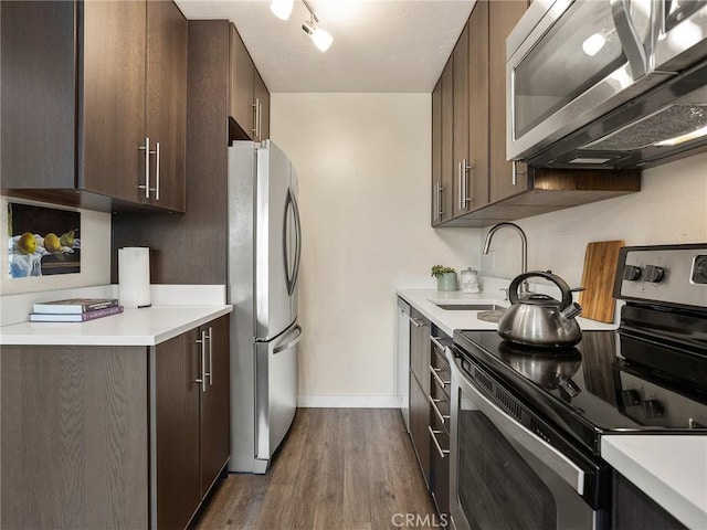 kitchen featuring dark brown cabinets, dark wood-type flooring, light countertops, appliances with stainless steel finishes, and a sink