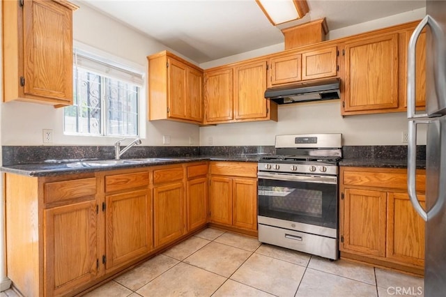 kitchen with under cabinet range hood, light tile patterned floors, brown cabinets, stainless steel appliances, and a sink