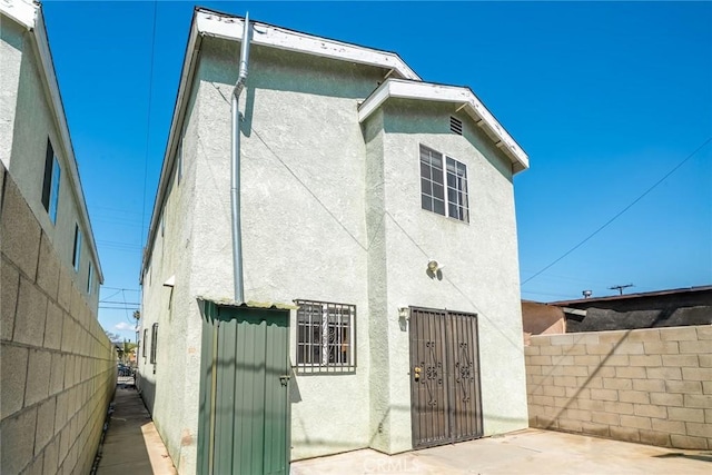 rear view of house with stucco siding, a patio area, and fence