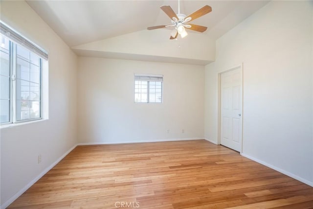 empty room with vaulted ceiling, light wood-style flooring, a ceiling fan, and baseboards