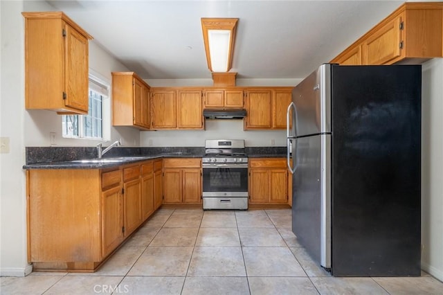 kitchen featuring under cabinet range hood, light tile patterned floors, brown cabinetry, stainless steel appliances, and a sink