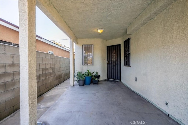 doorway to property featuring a patio area, fence, and stucco siding