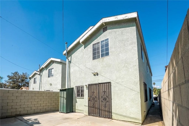 view of property exterior featuring a patio area, stucco siding, and fence