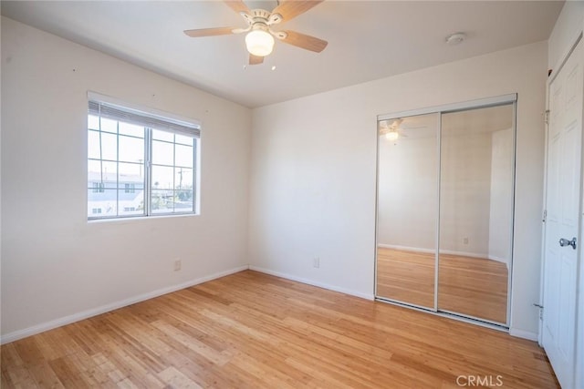 unfurnished bedroom with light wood-style flooring, baseboards, a closet, and ceiling fan