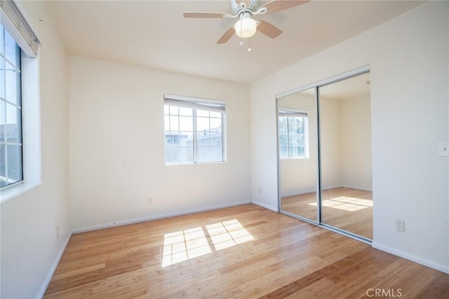 unfurnished bedroom featuring a ceiling fan, wood finished floors, a closet, and baseboards