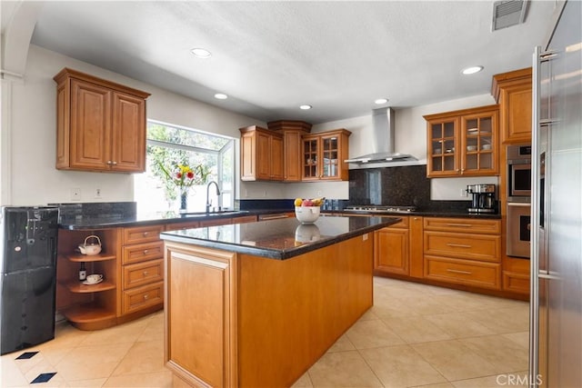 kitchen with visible vents, brown cabinets, a kitchen island, and wall chimney exhaust hood