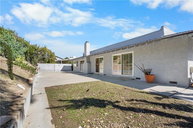 back of house featuring stucco siding, fence, crawl space, a chimney, and a patio area