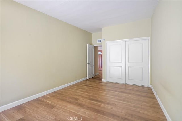 unfurnished bedroom featuring visible vents, baseboards, a closet, and light wood finished floors