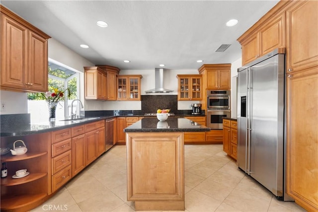 kitchen featuring visible vents, a kitchen island, stainless steel appliances, wall chimney exhaust hood, and a sink