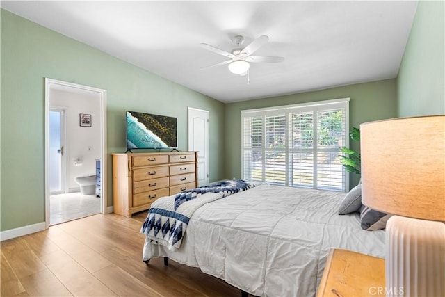 bedroom featuring ensuite bathroom, baseboards, wood finished floors, and a ceiling fan