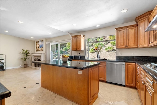 kitchen featuring a center island, recessed lighting, appliances with stainless steel finishes, a fireplace, and a sink