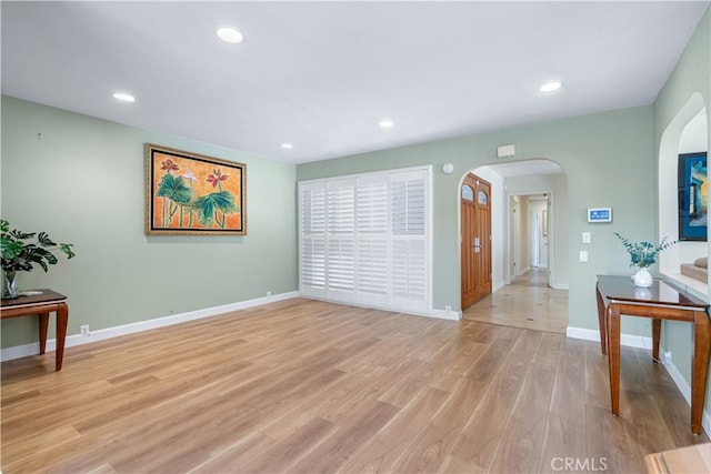 living room featuring recessed lighting, arched walkways, and light wood finished floors