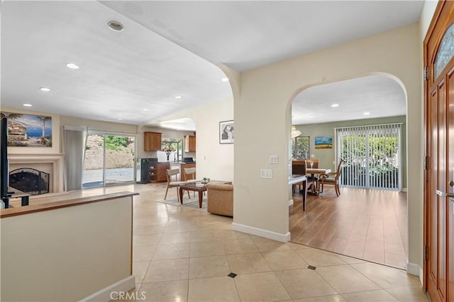 hallway featuring arched walkways, light tile patterned floors, and recessed lighting