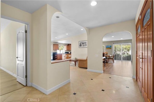 hall featuring light tile patterned floors, recessed lighting, and arched walkways