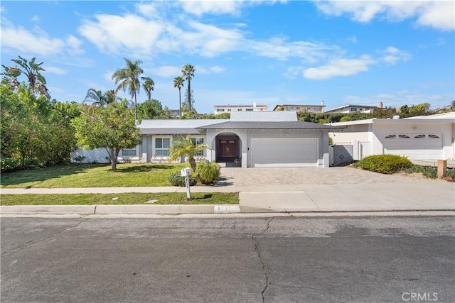 view of front of property featuring a front yard, decorative driveway, a garage, and stucco siding