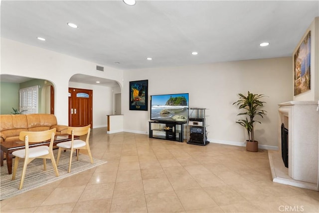 living area with baseboards, light tile patterned floors, recessed lighting, a fireplace, and arched walkways