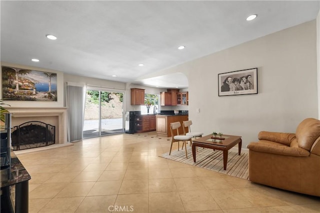 living area with vaulted ceiling, recessed lighting, a fireplace with raised hearth, and light tile patterned flooring