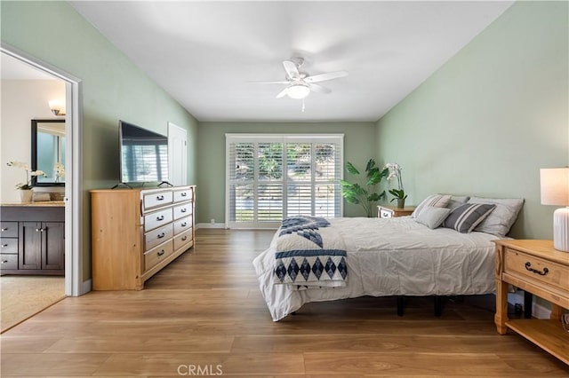 bedroom with ensuite bathroom, baseboards, light wood-type flooring, and ceiling fan