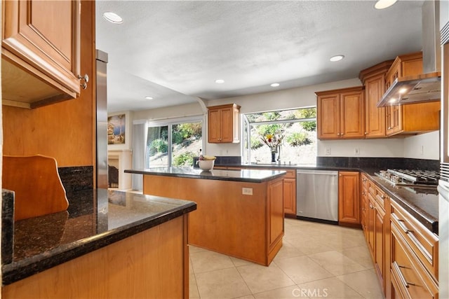 kitchen with a fireplace, a sink, stainless steel appliances, brown cabinets, and a center island