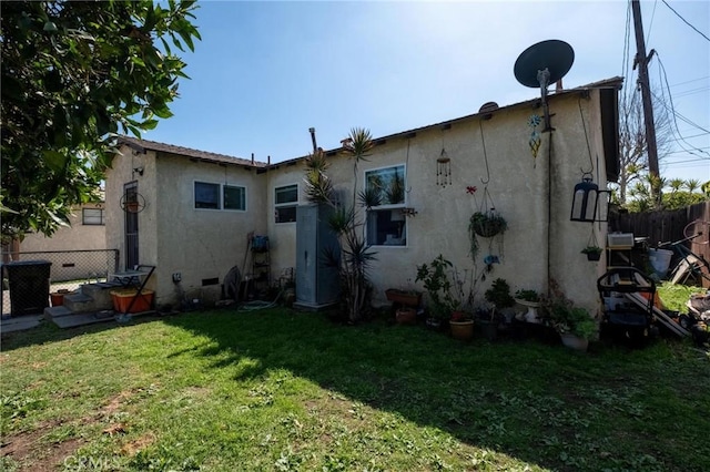 rear view of house with crawl space, stucco siding, a lawn, and fence