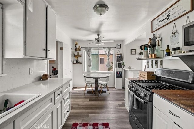 kitchen featuring a ceiling fan, stainless steel microwave, dark wood-style floors, gas stove, and white cabinets