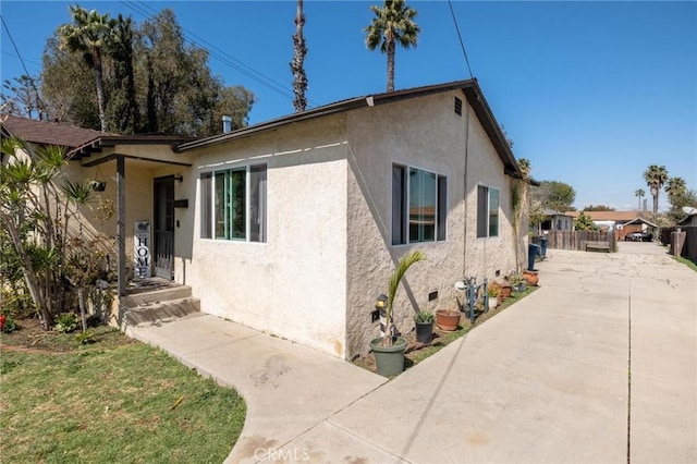 view of front facade featuring crawl space, stucco siding, and fence