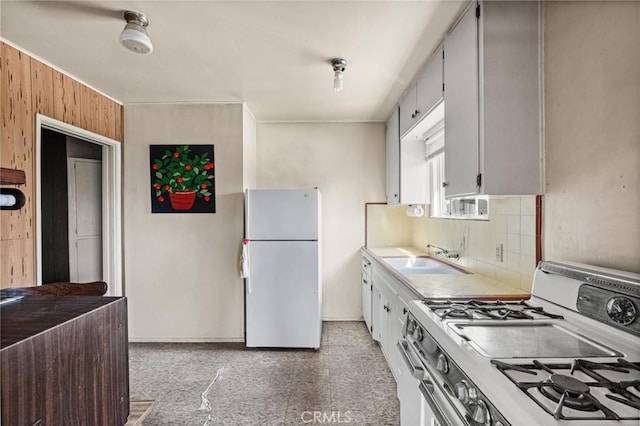 kitchen featuring wooden walls, backsplash, tile counters, white appliances, and a sink