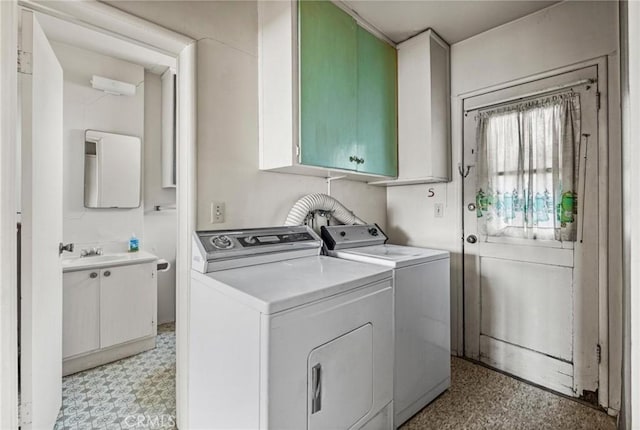 clothes washing area with a sink, cabinet space, light floors, and washer and clothes dryer