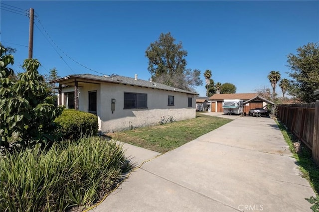 view of front facade featuring stucco siding, a front yard, and fence