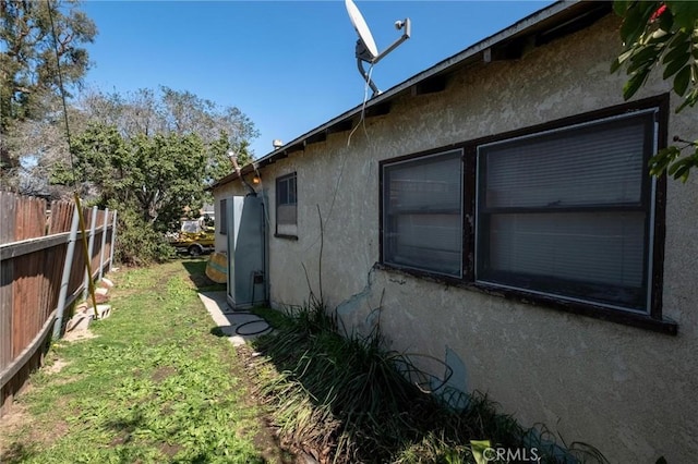 view of side of home with fence, a garage, and stucco siding