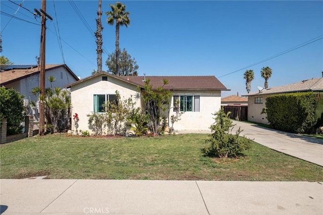 ranch-style home featuring concrete driveway, a front lawn, and stucco siding