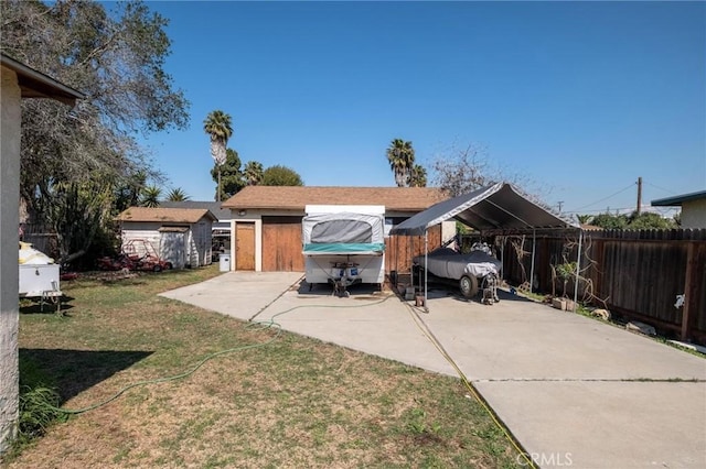 rear view of property with an outbuilding, a lawn, and fence