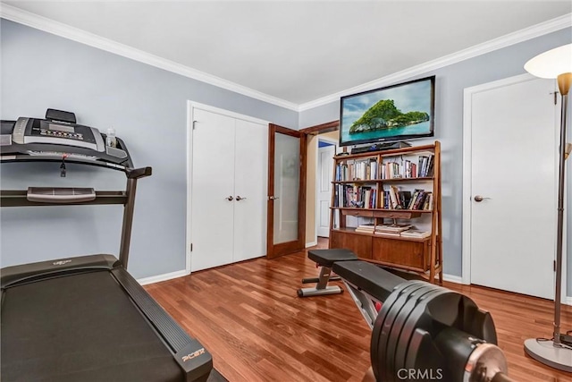 exercise area featuring baseboards, wood finished floors, and crown molding