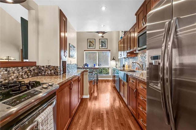 kitchen featuring stainless steel appliances, a sink, dark wood-type flooring, stone counters, and tasteful backsplash