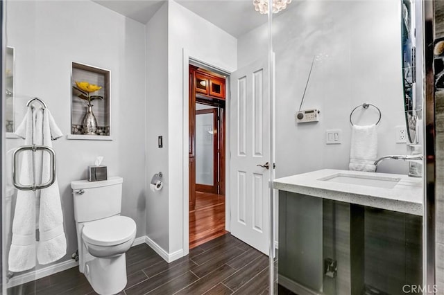 bathroom with vanity, toilet, baseboards, and wood tiled floor