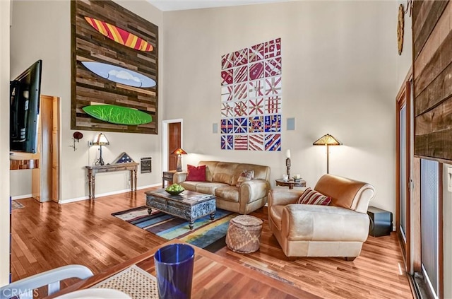 living room with baseboards, wood finished floors, and a towering ceiling