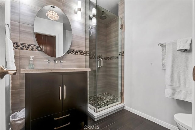 full bathroom featuring vanity, a shower stall, toilet, and baseboards